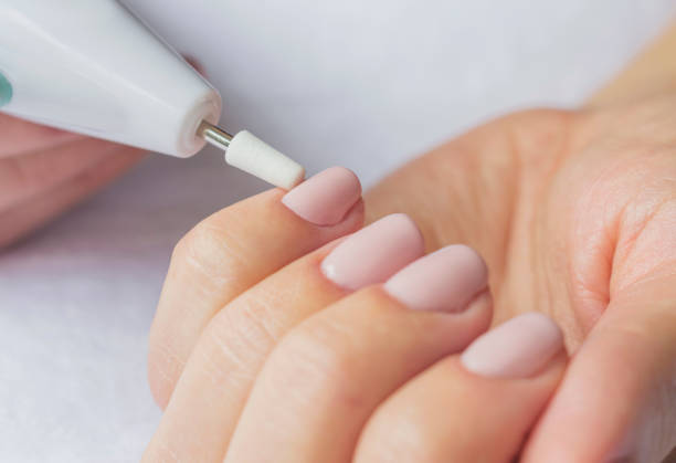 istock Manicure. Female hands with electric nail trimmer. 876601158