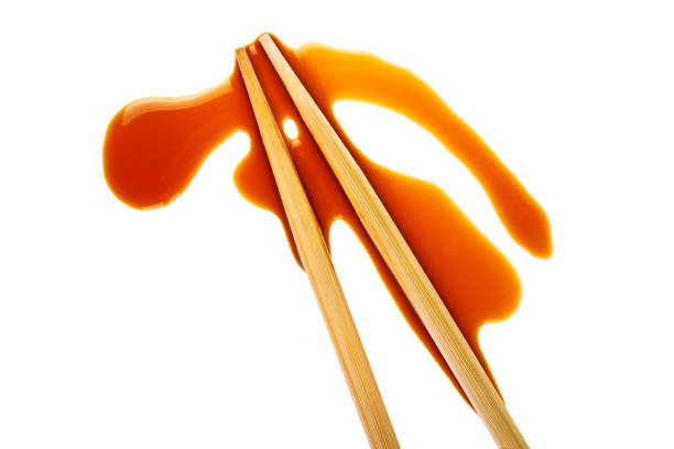 istock Splashes of soy sauce and chopsticks isolated on white background 876604120