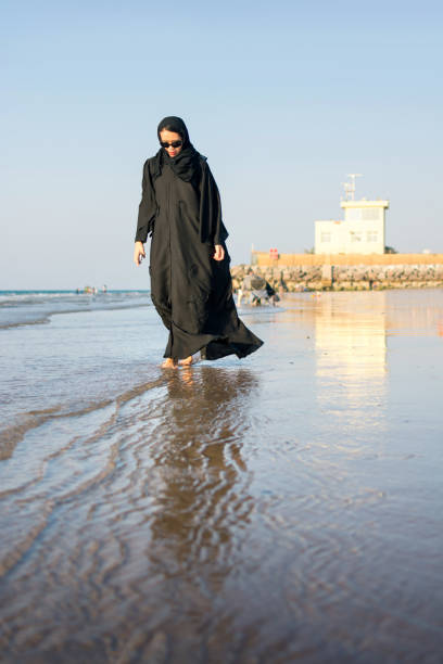 istock Woman in hijab walking on the beach 876604142