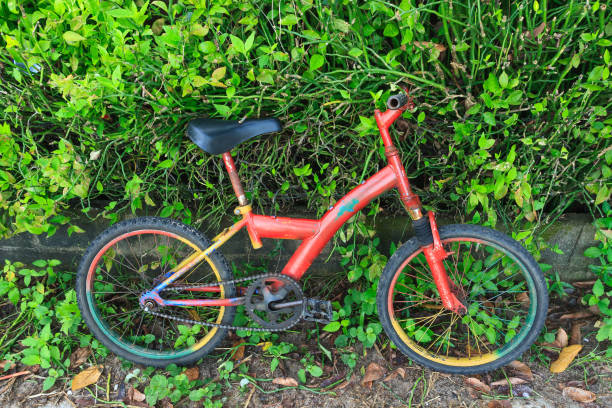 istock Old red Children's bicycle against gree tree background. 876604456