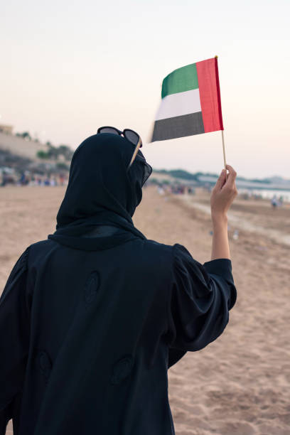 femme tenant le drapeau des émirats arabes unis sur la plage - flag of the united arab emirates photos et images de collection