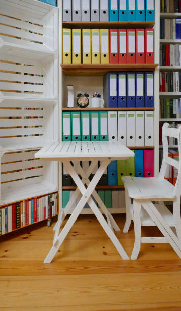 istock Office: Colorful ring binders in a wooden shelf and desk in front 876608512