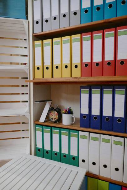 istock Office: Colorful ring binders in a wooden shelf and desk in front 876608570