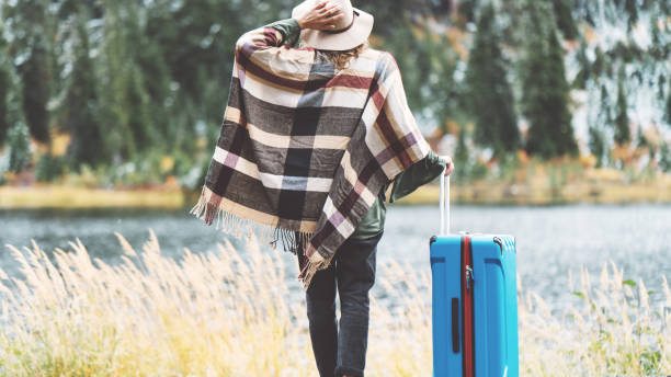 istock Traveling woman with bright blue suitcase looking at mountain wilderness 876616562
