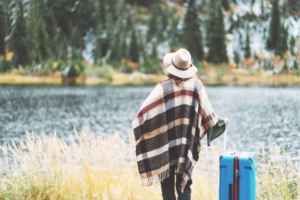 istock Traveling woman with bright blue suitcase looking at mountain wilderness 876616890