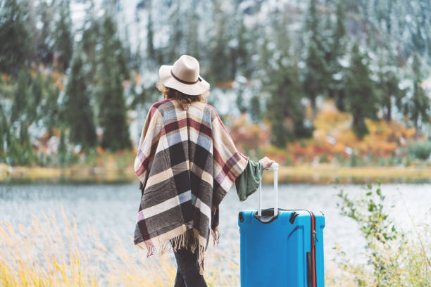 istock Traveling woman with bright blue suitcase looking at mountain wilderness 876616892