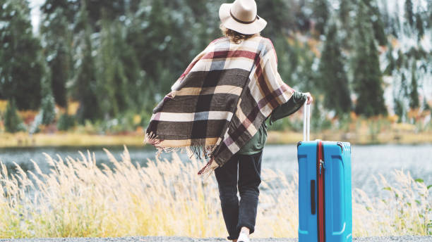 istock Traveling woman with bright blue suitcase looking at mountain wilderness 876616894