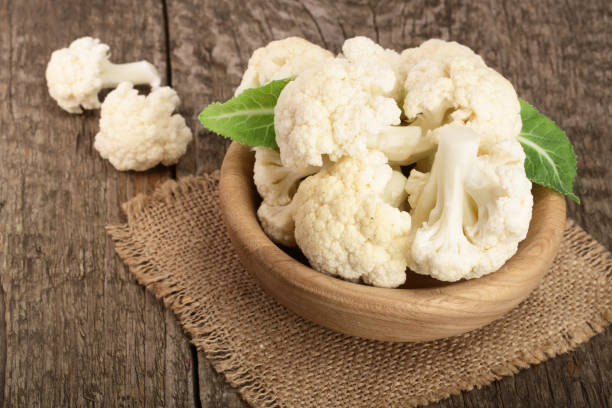 istock Fresh cauliflower cut into small pieces in wooden bowl on rustic background 876617146