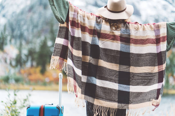 istock Traveling woman with bright blue suitcase looking at mountain wilderness 876619426