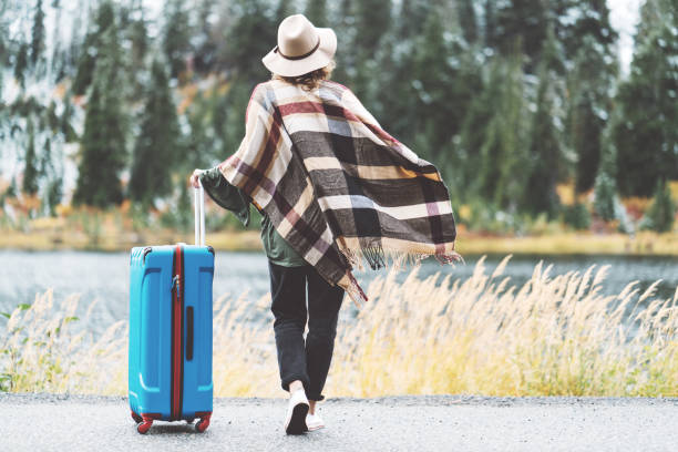 istock Traveling woman with bright blue suitcase looking at mountain wilderness 876621550