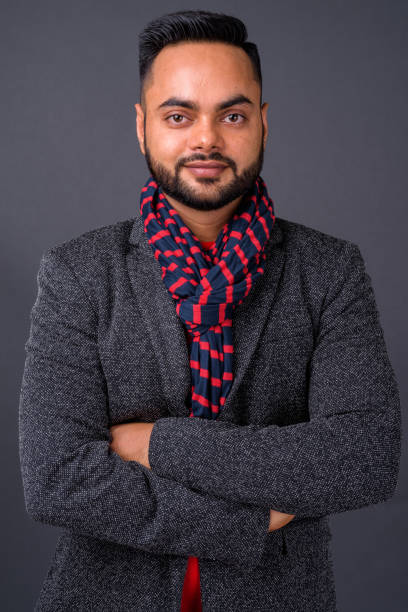 istock Young bearded Indian businessman against gray background 876625198