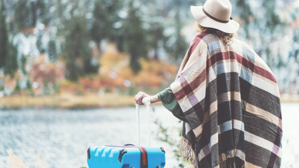 istock Traveling woman with bright blue suitcase looking at mountain wilderness 876625330