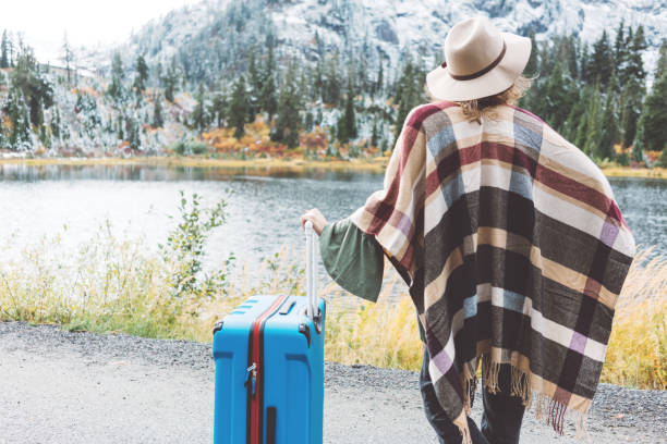 istock Traveling woman with bright blue suitcase looking at mountain wilderness 876625464