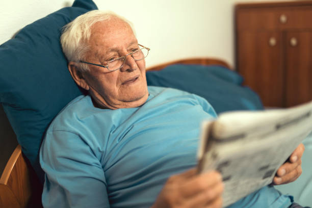istock Senior man in glasses reading newspaper at home 876626096