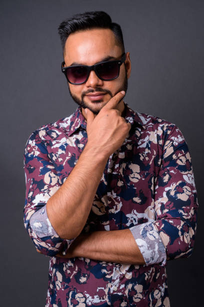 istock Young bearded Indian man against gray background 876629038