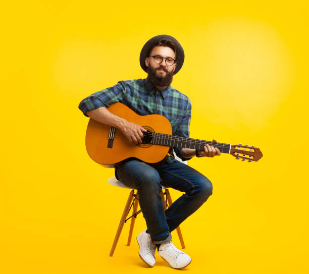 jeune homme avec une guitare en studio - musical instrument people music young adult photos et images de collection