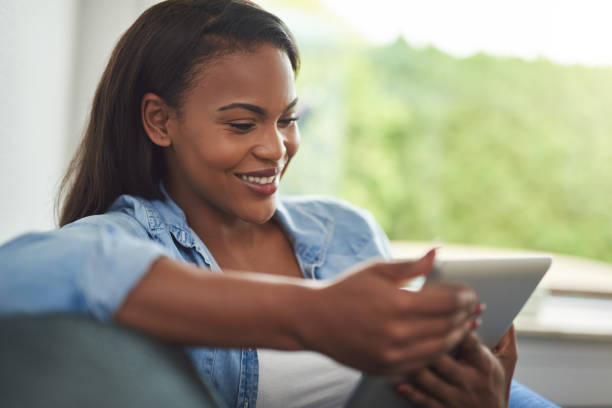 istock Smiling African woman sitting at home using a digital tablet 876630126