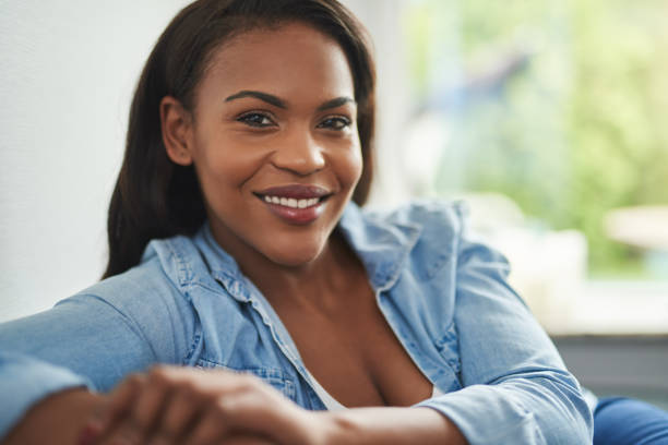 istock Smiling young African woman sitting on her sofa at home 876633272