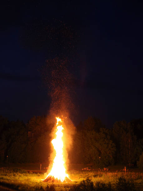 Couple stand in-front of a large bonfire at night