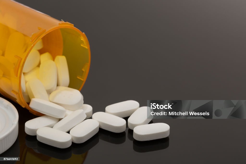 Pills spilled out on table Opioid pain killer other pills spilled out on table with reflective surface with gradient Capsule - Medicine Stock Photo