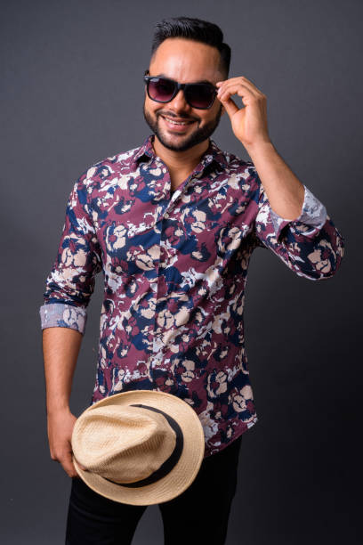 istock Young bearded Indian tourist man against gray background 876641978