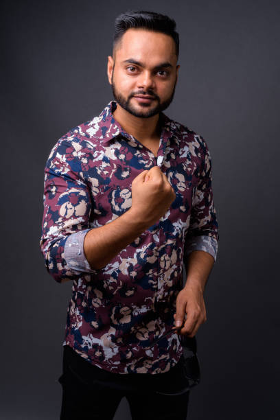 istock Young bearded Indian man against gray background 876642196