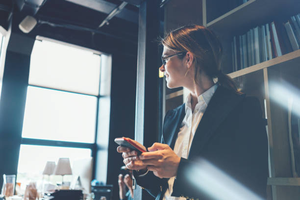istock Business woman with mobile phone standing in open space office 876649446