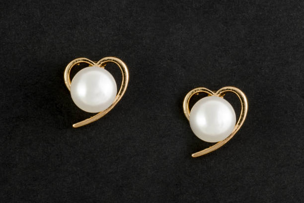istock gold earrings hearts with pearls isolated on black 876656206