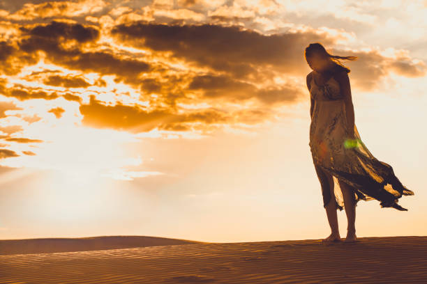 istock slim girl standing in the sand dunes 876656802