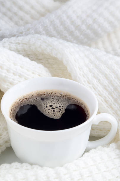 istock White cup with hot coffee wrapped in a white woolen scarf 876660796