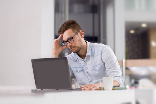 istock Pensive businessman reading something from laptop at office. 876666912