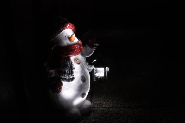 Snowman holding a lamp on a dark Christmas night stock photo