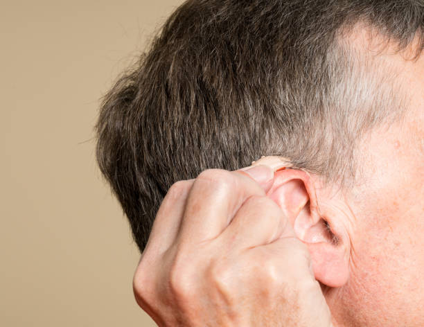 istock Close up of a tiny modern hearing aid behind ear 876670880