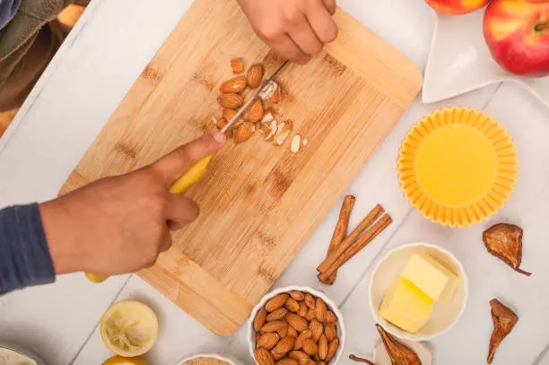 Boys Hands Cutting Almonds on Wooden Cuting Board