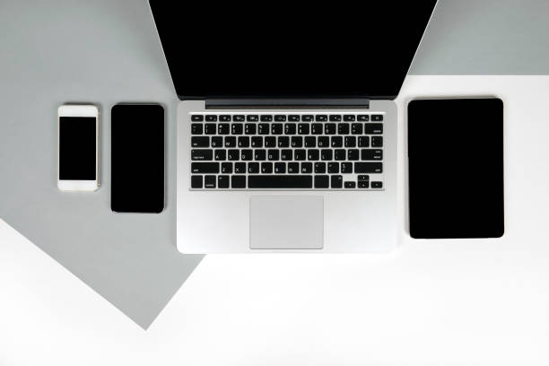 istock Flat lay photo of Office table with laptop computer, notebook, digital tablet and mobile phone on modern two tone (white and grey) background. Desktop office mockup concept. 876689290