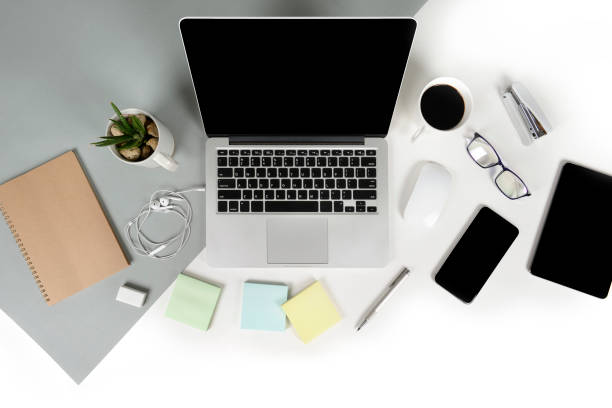 istock Flat lay photo of Office table with laptop computer, notebook, digital tablet, mobile phone, Pencil, eyeglasses  on modern two tone (white and grey) background. Desktop office mockup concept. 876689370