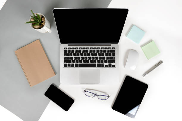 istock Flat lay photo of Office table with laptop computer, notebook, digital tablet, mobile phone, Pencil, eyeglasses  on modern two tone (white and grey) background. Desktop office mockup concept. 876689492