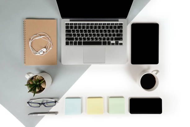 istock Flat lay photo of Office table with laptop computer, notebook, digital tablet, mobile phone, Pencil, eyeglasses  on modern two tone (white and grey) background. Desktop office mockup concept. 876689540