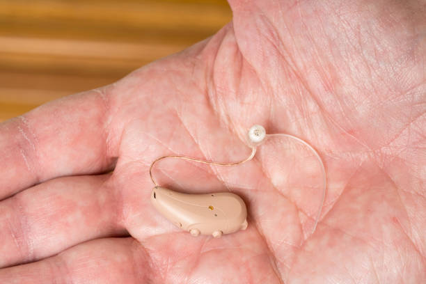 istock Close up of a tiny modern hearing aid in palm 876690186