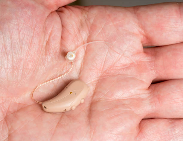 istock Close up of a tiny modern hearing aid in palm 876690418