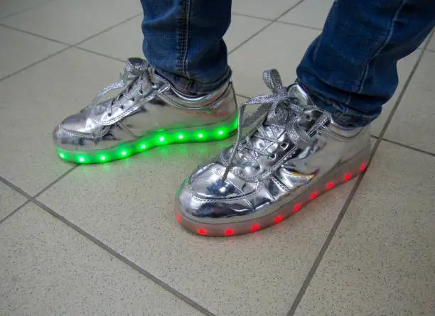Photo of Fashionable sneakers with LED lighting on the legs of people