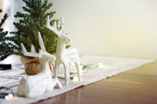 istock Deer Christmas decorations with lights and trees and golden light shining on table 876704830