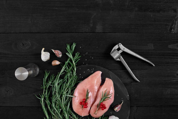 chicken breast on a cutting board with herbs, spices and garlic press on rustic wooden background - garlic chicken breast raw chicken imagens e fotografias de stock