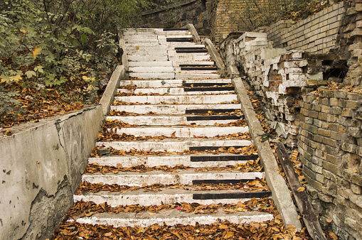 Abandoned stairs, are painted in the style of piano keys surrounded by autumn fallen yellow leaves and collapsed walls. Concept, symbolizing autumn sad music, song or a symphony