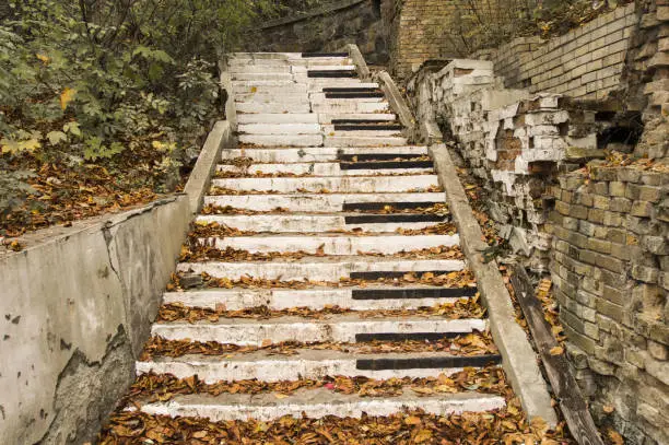 Photo of Abandoned stairs, are painted in the style of piano keys surrounded by autumn fallen yellow leaves and collapsed walls. Concept, symbolizing autumn sad music, song or a symphony