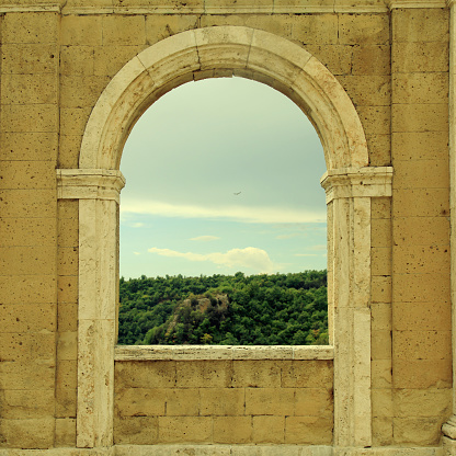 Italian view through the arch window in Sorano, Tuscany, Italy. Medieval wall with arch window in Italy