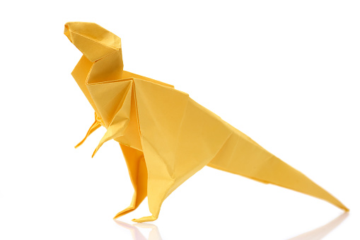 Yellow tyrannosaurus on white background. Kid's origami project, dinosaur theme. Creative work concept.