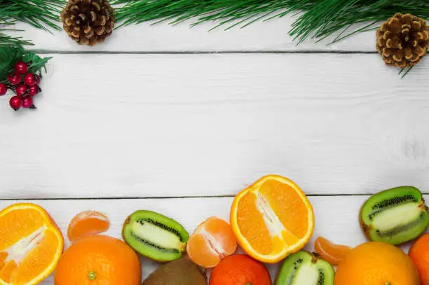 Fruit orange, tangerine and kiwifruit branch christmas tree cone  on white wooden rustic background