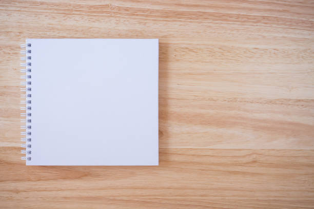 istock white cover notebook on brown wood desk background 876773828