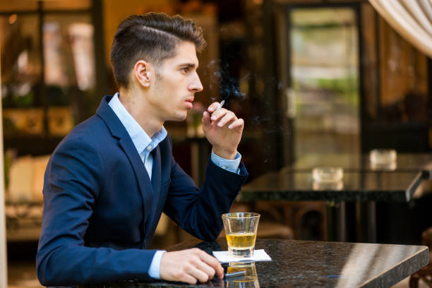 istock Young serious businessman smoking cigarette and drinking alcohol 876774242